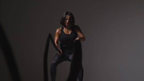 Studio-Shot-Of-Mature-Woman-Wearing-Gym-Fitness-Clothing-Doing-Cardio-Exercise-With-Battle-Ropes-3